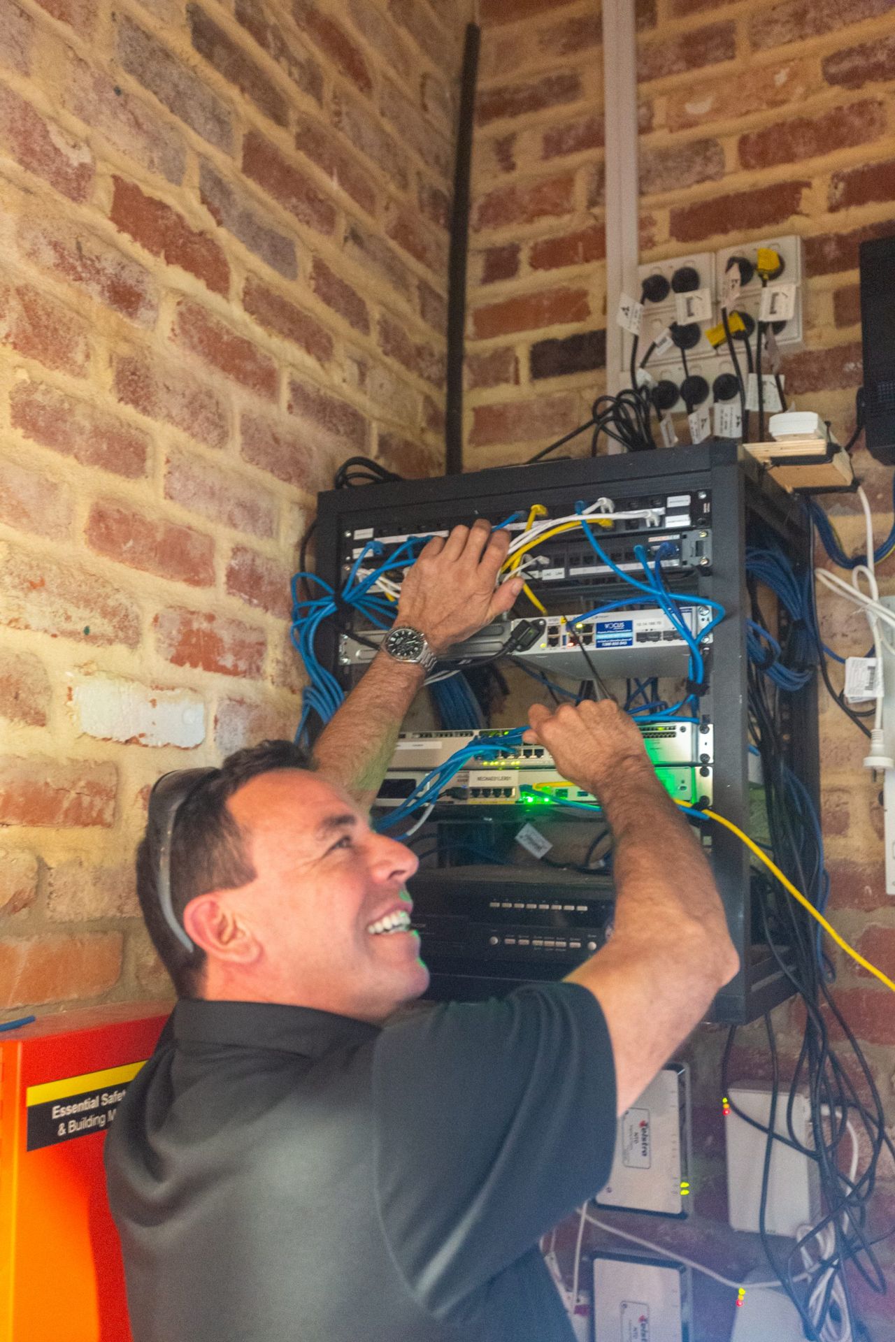 Hi-Tech Security technician working on network and security equipment in a comms rack